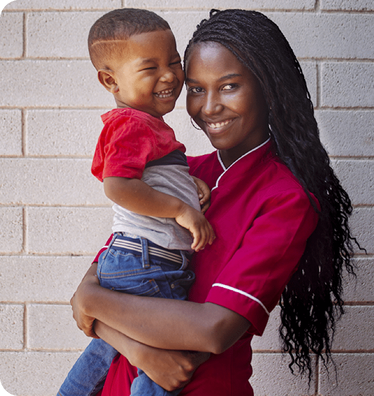 Mujer sonriente junto a su hijo cargado en los brazos